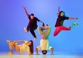 Group of young people, guys and girls in dancing contemporary dance, hip-hop, brakedance over blue background in neon Royalty Free Stock Photo