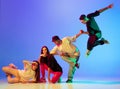 Group of young people, guys and girls in dancing contemporary dance, hip-hop, brakedance over blue background in neon Royalty Free Stock Photo