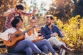 Young people hangout in the park.They sitting on bench ,singing and playing guitar Royalty Free Stock Photo