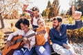 Young people hangout in the park.They sitting on bench ,singing and playing guitar Royalty Free Stock Photo