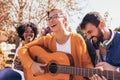Young people hangout in the park.They sitting on bench ,singing and playing guitar Royalty Free Stock Photo