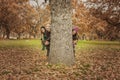 Group of young people hidden behind a tree. Autumn landscape