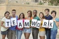 Group of young people holding teamwork sign