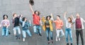 Group of young people jumping together outdoor - Happy millennial friends celebrating success in college