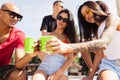 Group of young people, men and women resting on the beach, drinking cool drinks, having fun sunbathing Royalty Free Stock Photo