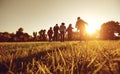 A group of young people running through the grass in the park at sunset. Royalty Free Stock Photo