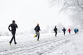 Group young people running together snowy trail in winter Park. rear view