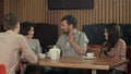 Group of young people sitting at a cafe, talking and enjoying Royalty Free Stock Photo