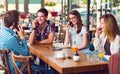 Group of young people sitting at a cafe, talking over phones Royalty Free Stock Photo