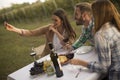 Group of young people sitting by the table and drinking red wine in the vineyard Royalty Free Stock Photo