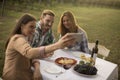 Group of young people sitting by the table and drinking red wine in the vineyard Royalty Free Stock Photo