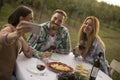 Group of young people sitting by the table and drinking red wine in the vineyard Royalty Free Stock Photo