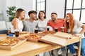 Group of young people smiling happy and hugging eating italian pizza at home Royalty Free Stock Photo