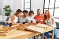 Group of young people smiling happy and hugging eating italian pizza at home Royalty Free Stock Photo