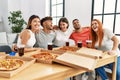 Group of young people smiling happy and hugging eating italian pizza at home Royalty Free Stock Photo