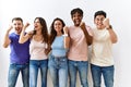 Group of young people standing together over isolated background angry and mad raising fist frustrated and furious while shouting Royalty Free Stock Photo