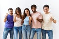 Group of young people standing together over isolated background very happy and excited doing winner gesture with arms raised, Royalty Free Stock Photo