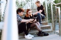 Group of young people students sitting on concrete stairs, preparing for exam. Young woman, curly man holding open book. Royalty Free Stock Photo