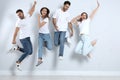 Group of young people in stylish jeans jumping near wall Royalty Free Stock Photo