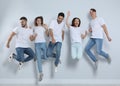 Group of young people in stylish jeans jumping near wall Royalty Free Stock Photo