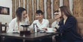 Group of young people from two couples of guys and girls have a tea time in the cafe and looking on the smartphone absorbedly Royalty Free Stock Photo