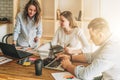 Group of young people working together. Man is using laptop, girls looking on screen of laptop, discussing business plan Royalty Free Stock Photo