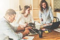 Group of young people working together. Man is using laptop, girls looking on screen of laptop, discussing business plan Royalty Free Stock Photo