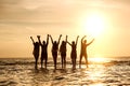 Group of young peoples stands in water at sunset Royalty Free Stock Photo