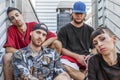 Group of young rappers posing sitting on the metal stairs