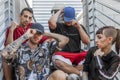 Group of young rappers posing sitting on the metal stairs