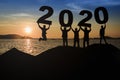 A group of young, sleek silhouettes of people who look happy and ready to hold the numbers 2020 and sunset as the background Royalty Free Stock Photo