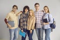 Group of young smart students with backpacks on their shoulders and textbooks in their hands. Royalty Free Stock Photo