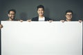 A group of young, smiling and professional business men holding a white sign copyspace portrait. A team of male Royalty Free Stock Photo