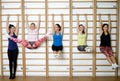 Group of young sports woman does an extension exercise at the Swedish wall