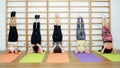 Group of young sports woman does an extension exercise at the Swedish wall