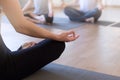 Group of young sporty people practicing yoga with instructor, sitting in Sukhasana exercise