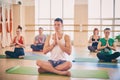 Group of young sporty people practicing yoga lesson with instructor, sitting in Padmasana exercise, Lotus pose with folded hands i Royalty Free Stock Photo