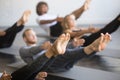 Group of young sporty people in Paripurna Navasana pose