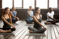 Group of young sporty people sitting in parivritta sukhasana