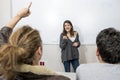 Group of young students taking lesson at University classroom with girl standing on blackboard explaining and pupils sitting on de