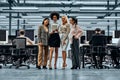 A group of young successful business women working together standing in the middle of the office and looking at a tablet. In the Royalty Free Stock Photo