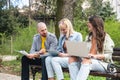 Group of young successful generation z hipster people sitting in park working on laptop computer researching business plan and Royalty Free Stock Photo