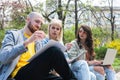 Group of young successful generation z hipster people sitting in park working on laptop computer researching business plan and Royalty Free Stock Photo