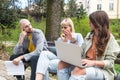 Group of young successful generation z hipster people sitting in park working on laptop computer researching business plan and Royalty Free Stock Photo