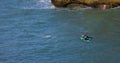 A group of young surfers and swimmers swim in the Atlantic ocean with big waves close to the shore on a sunny day