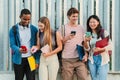 Group of young teenage high school students smiling and having fun using a social media app with smartphones. University Royalty Free Stock Photo