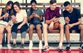 Group of young teenager friends on a basketball court relaxing using smartphone