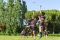 Group of young teenagers people in team wear playing a frisbee game in park oudoors. jumping man catch a frisbee to a teammate in