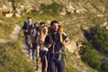 Group of young tourists hikers walking along mountain valley during traveling Royalty Free Stock Photo