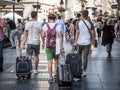 Group of Young travellers walking with their suitcases on Kneza Mihalova street in the middle of a crowd.